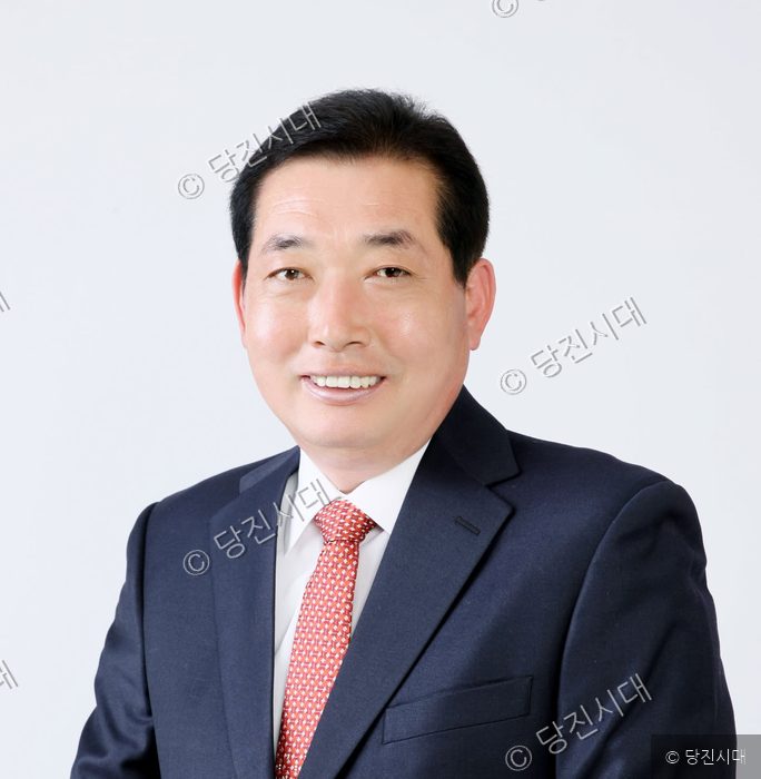 김명진 출마예정자가 정장 차림으로 미소를 짓고 있다.