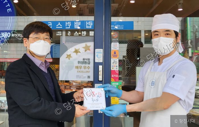 두 남성이 송악사회복지관의 '마음 잇는 동네' 1호 현판을 함께 들고 있다.